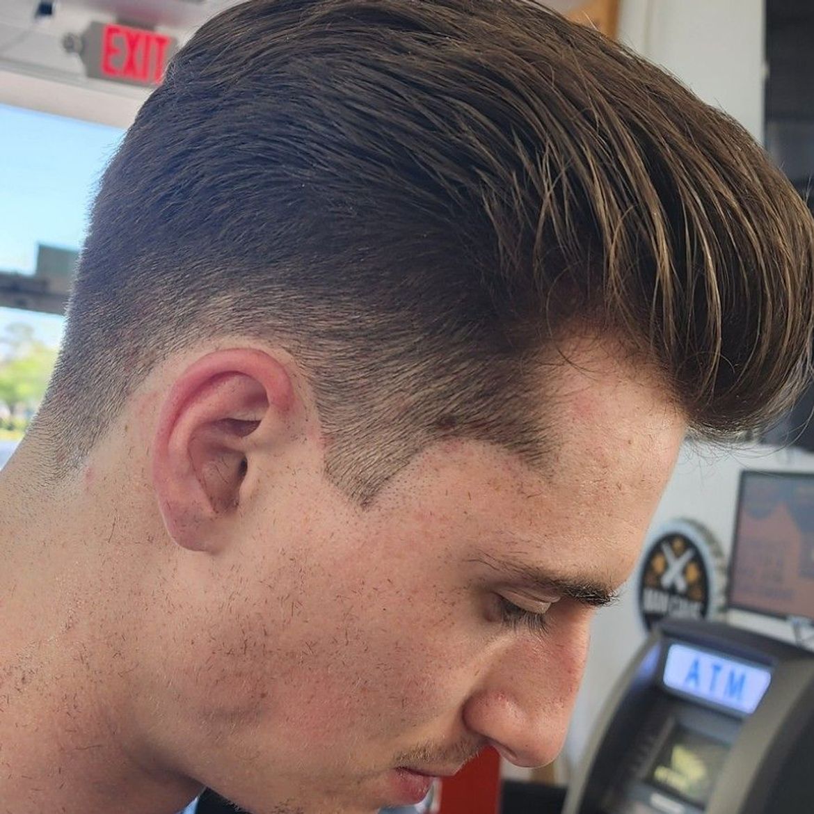 a man is looking down in front of an atm machine