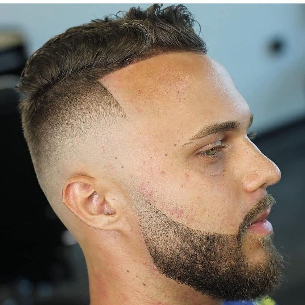 a man with a beard is getting his hair cut at a barber shop .