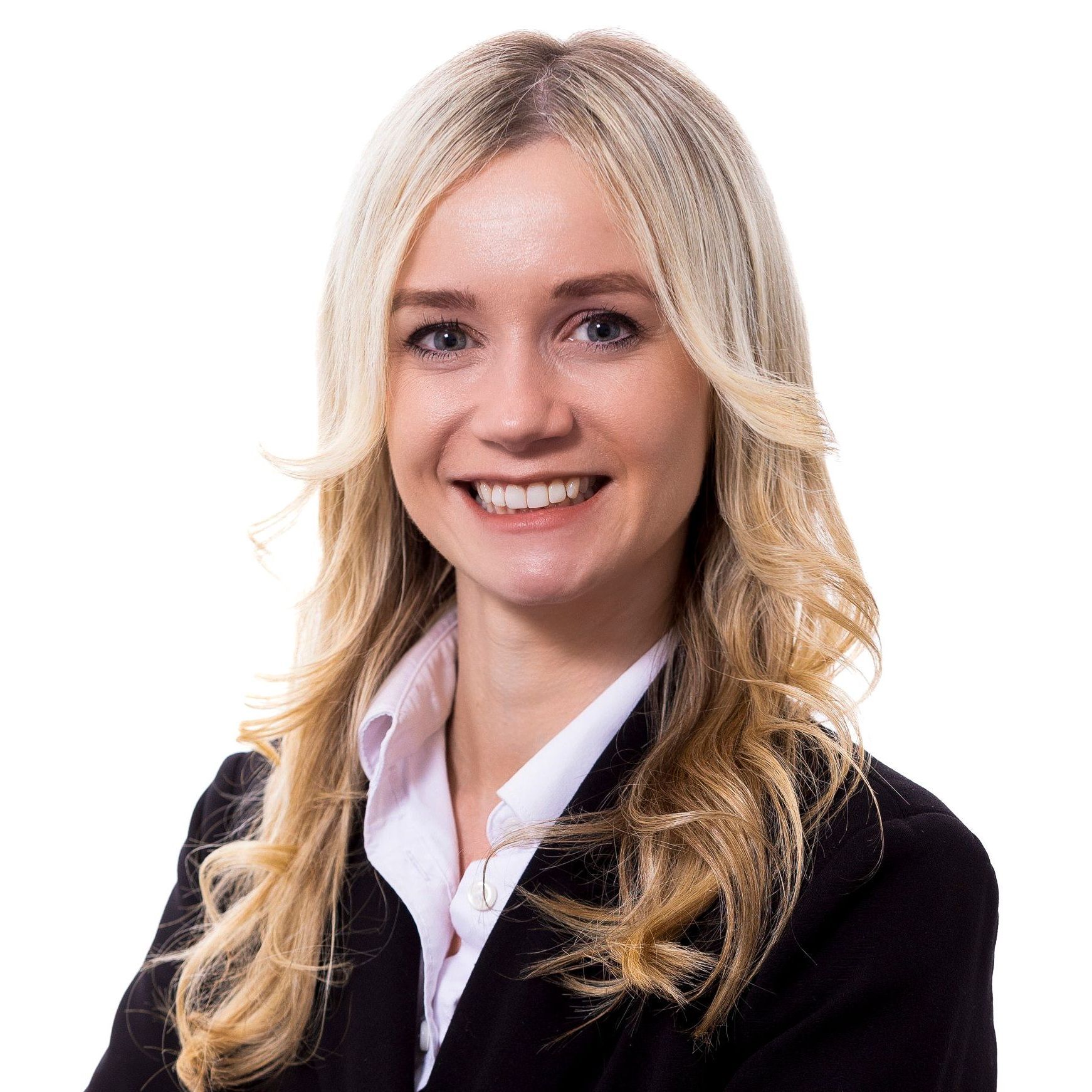 A woman in a suit and white shirt is smiling for the camera.