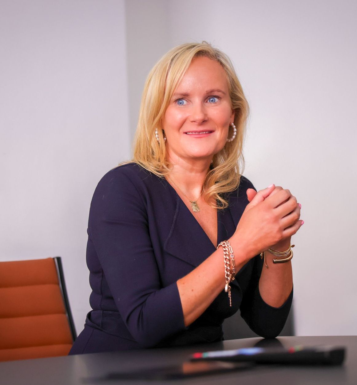 A woman is sitting at a table with her hands folded