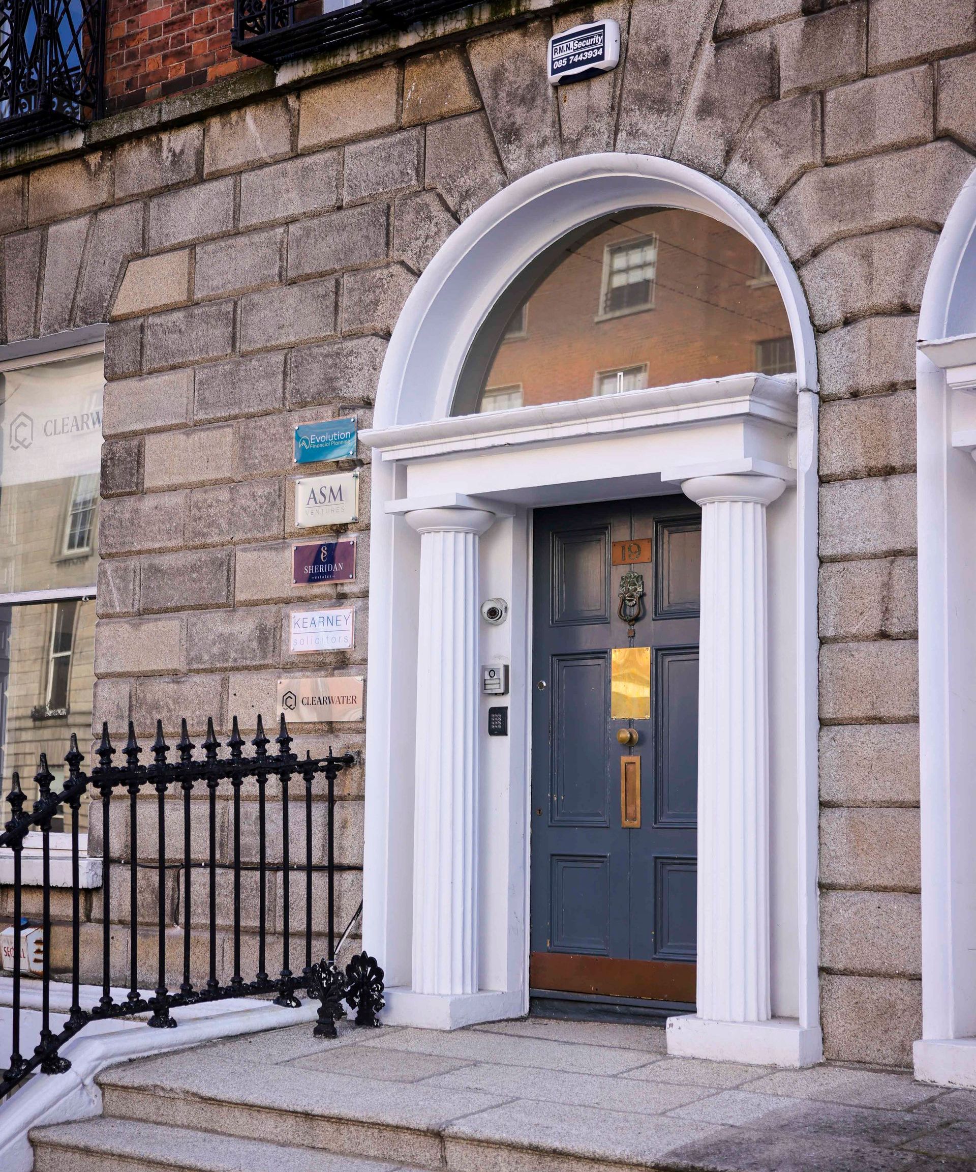 A brick building with a gray door and a white arch