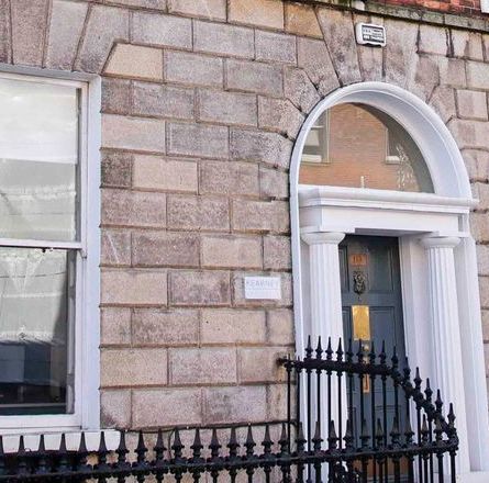 A brick building with a blue door and stairs