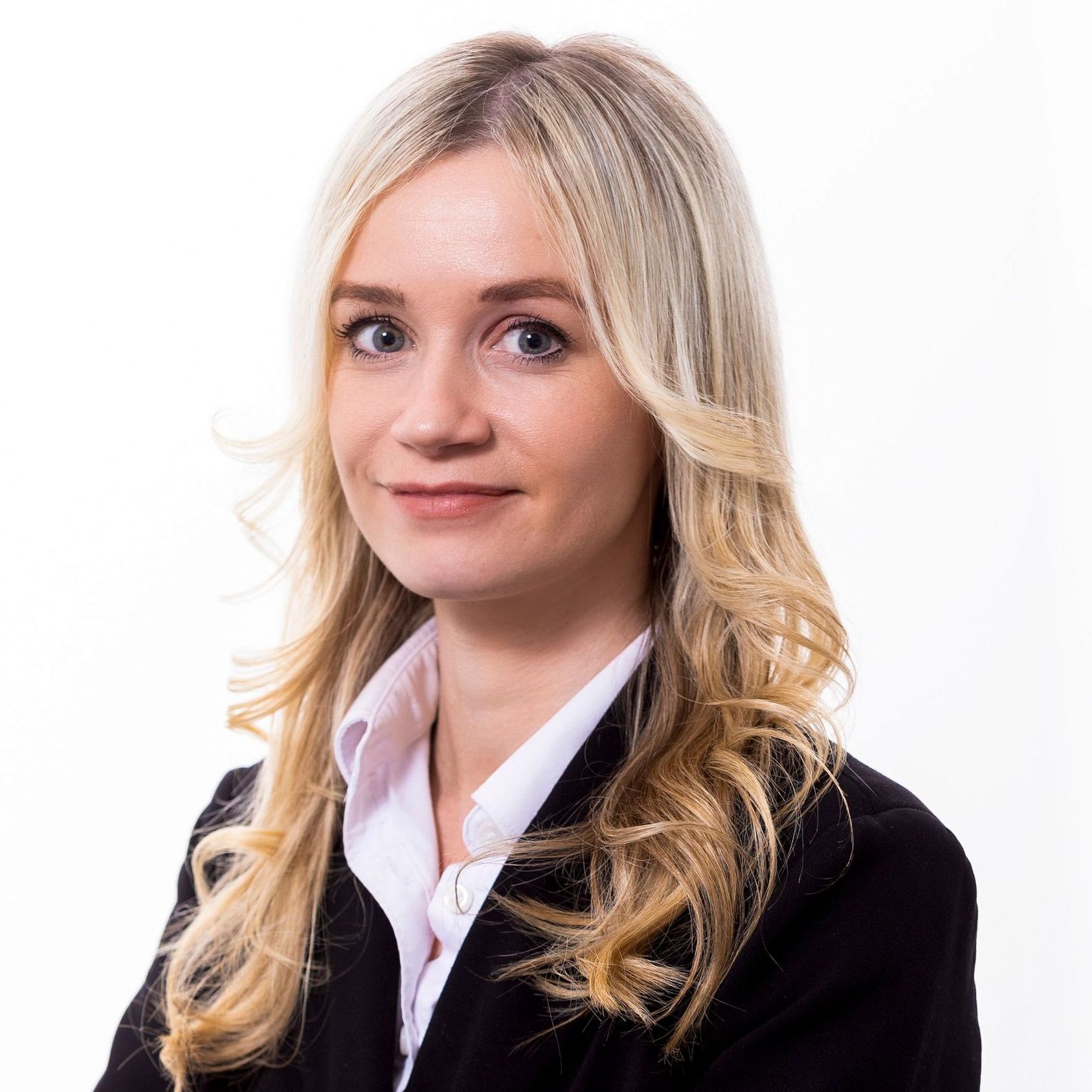 A woman with blonde hair is wearing a black jacket and white shirt.