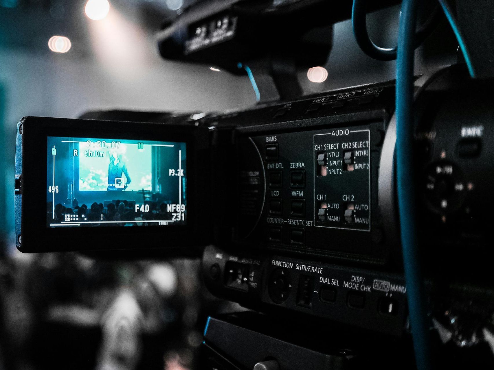 A video camera is recording a video of a man standing in front of a crowd.