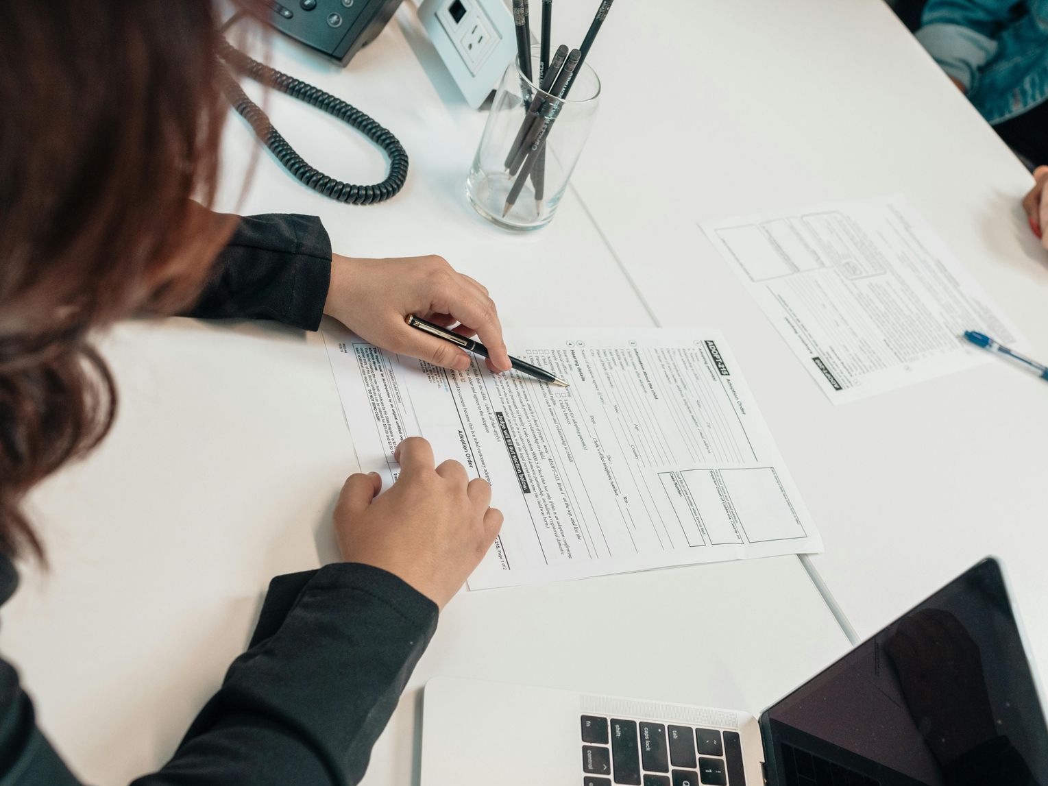 A woman is sitting at a table writing on a piece of paper.