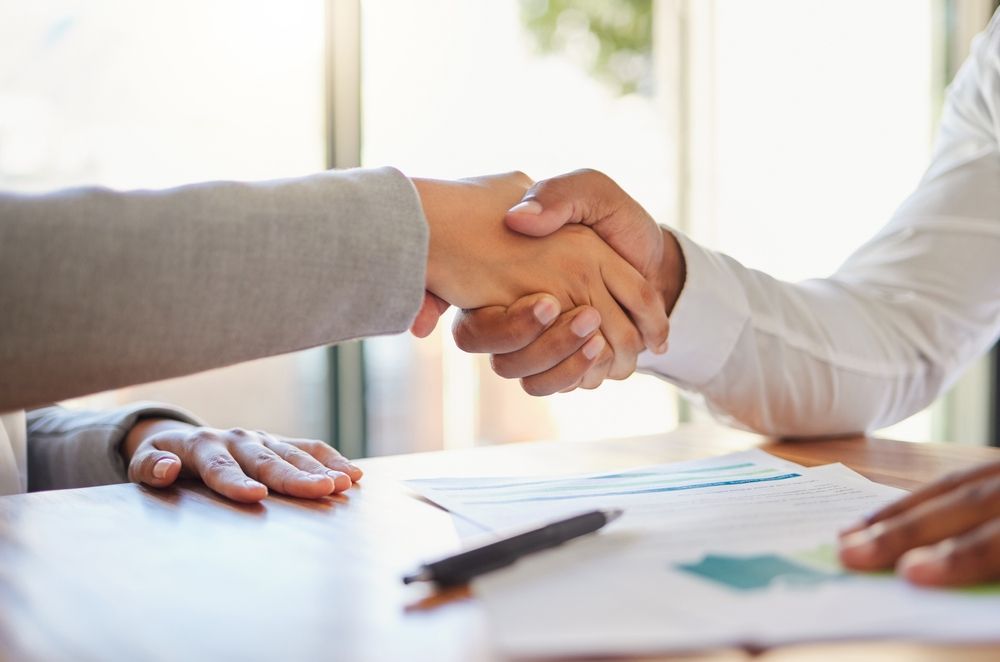 A man and a woman are shaking hands over a table, hiring an interim CFO
