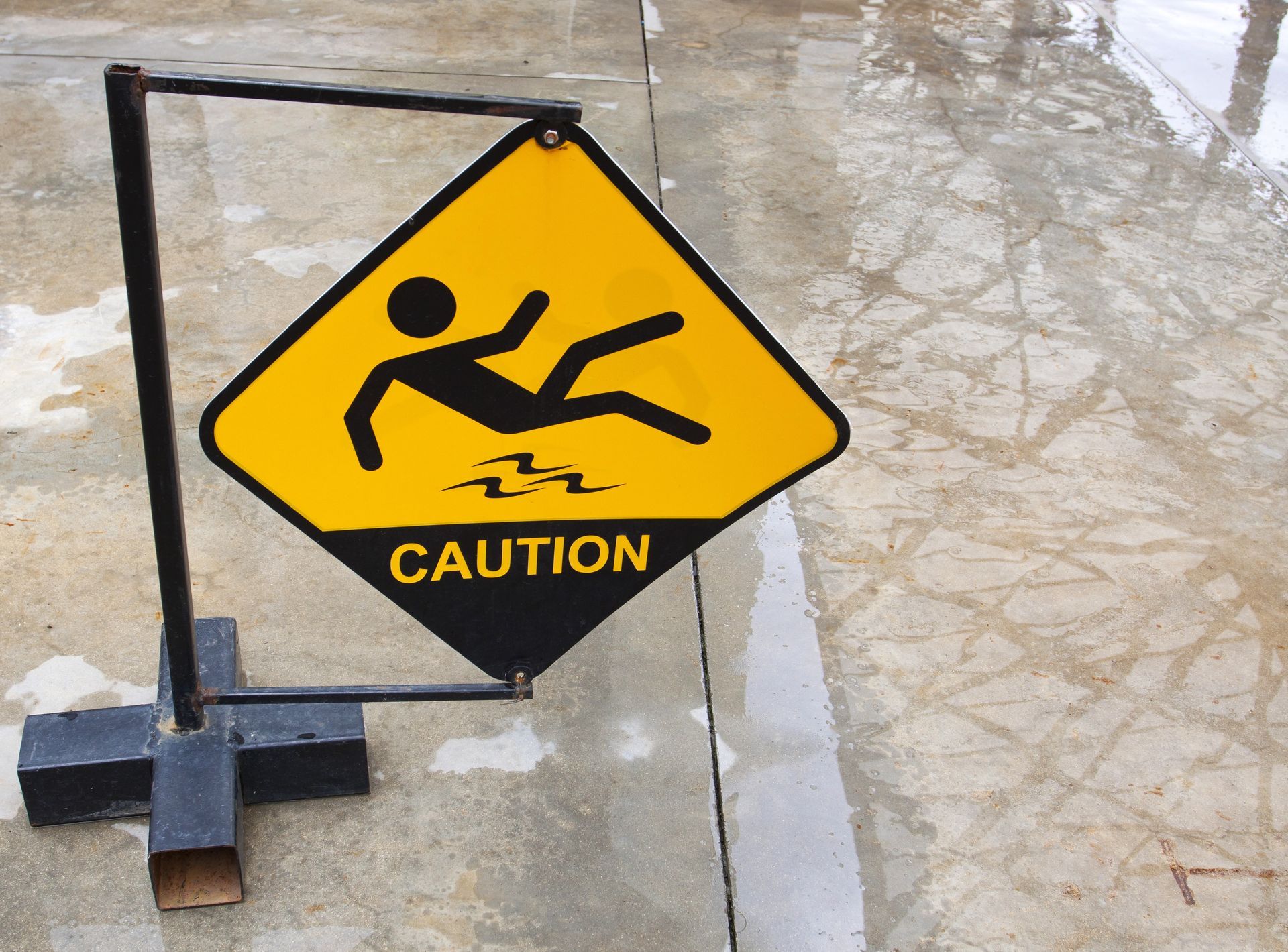 Yellow caution sign with a falling person symbol, warning of slippery surface.