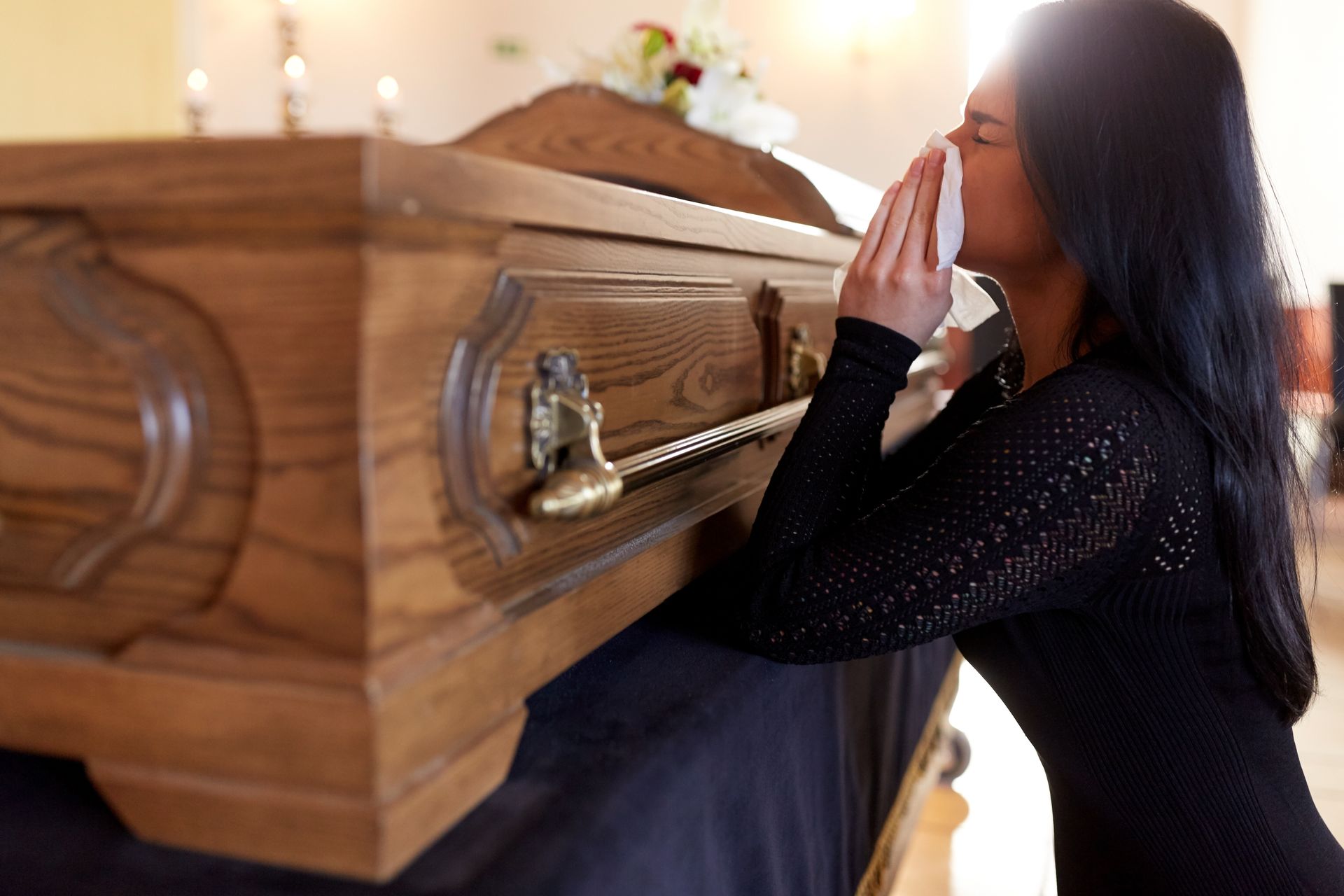 Woman crying at a wooden casket, representing wrongful death attorney.