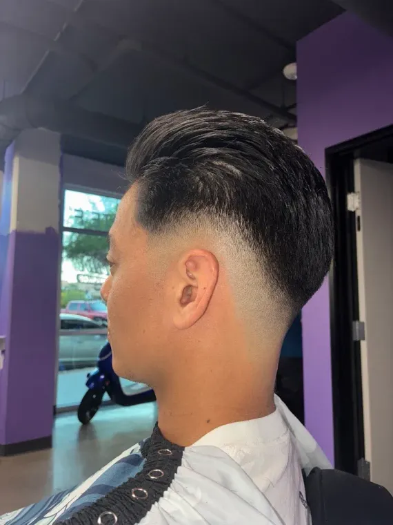 Profile view of a person with a short, faded haircut and styled hair on top, taken inside a salon.