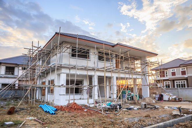 A house is being built in a residential area with scaffolding around it.