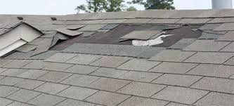 Damaged asphalt shingle roof with missing and curling shingles.