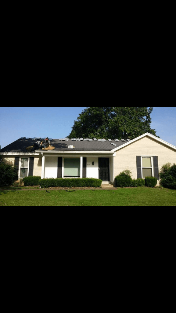 Ranch-style house with damaged roof, black shutters, white siding, and green lawn.