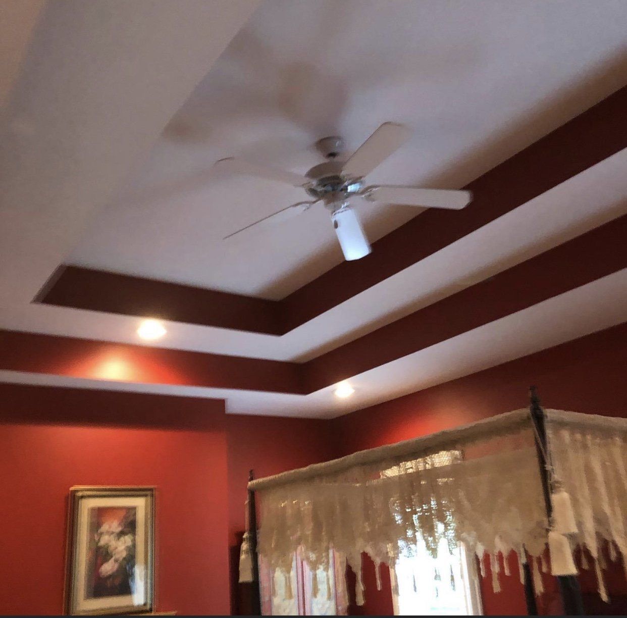 Red-walled bedroom with a white ceiling fan and recessed lighting. Dark wood trim. A bed is partially visible.
