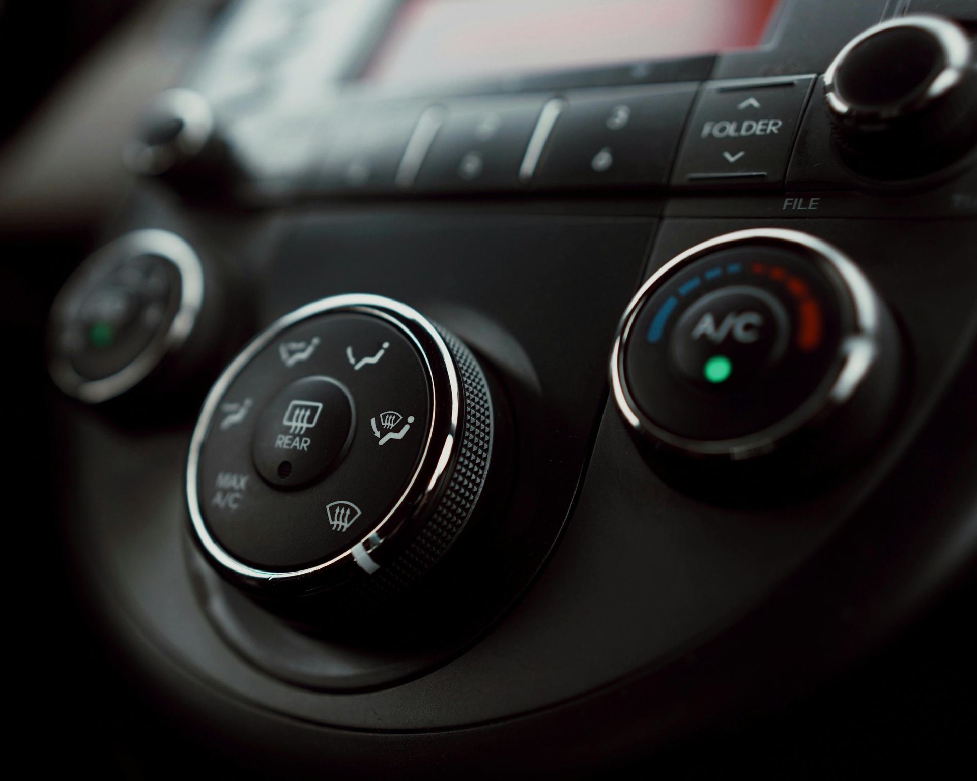 Car's dashboard controls, black and silver, with knobs for ventilation and air conditioning.