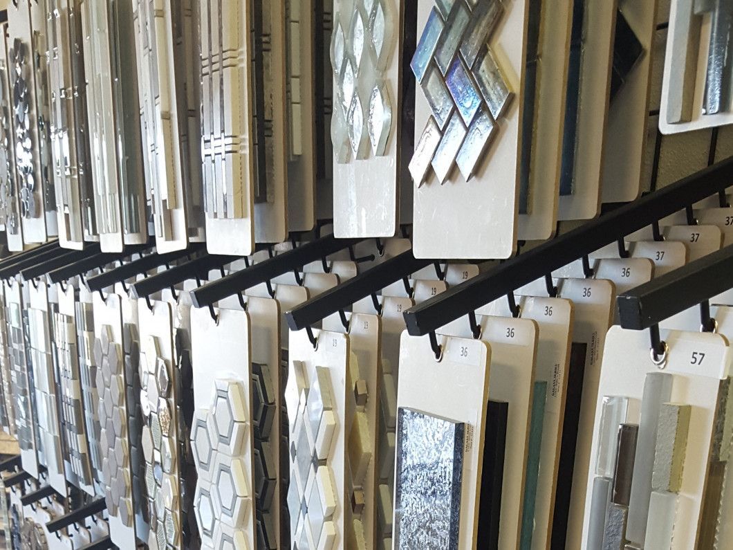 Rows of decorative tiles and stone samples displayed on angled racks in a showroom.