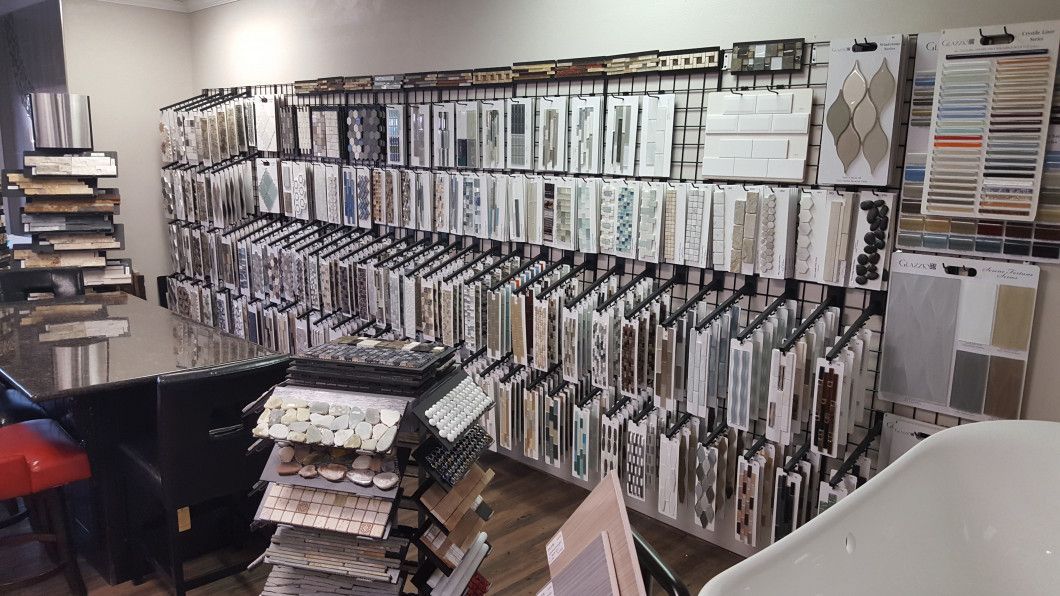 Fabric store aisle with rows of hanging textiles, sample books, and stacked materials.