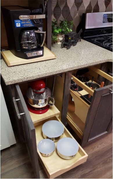 Kitchen cabinet with pull-out shelves holding a coffee maker, stand mixer, and bowls under a countertop