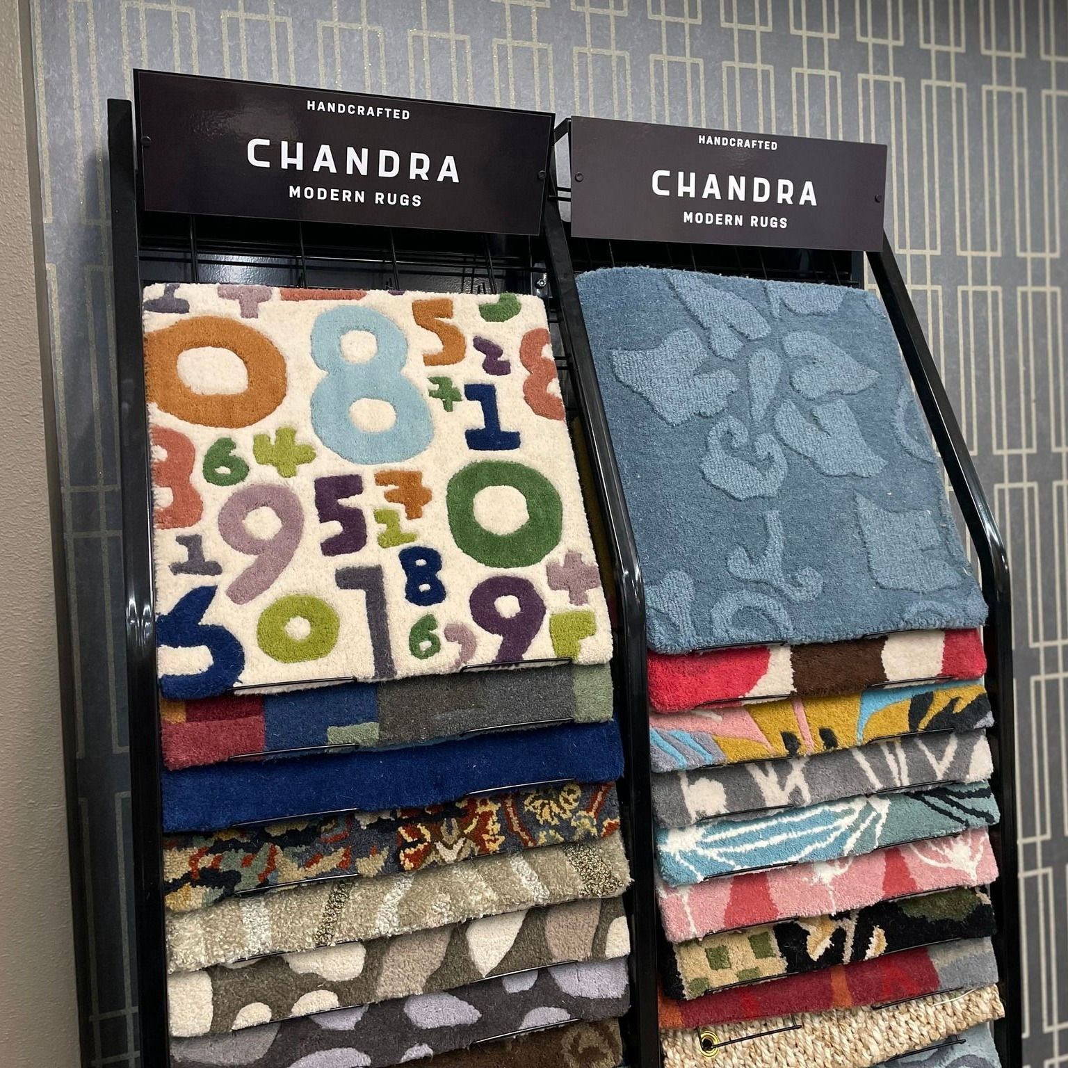 Two stacks of folded patterned fabrics with black CHANDRA labels on display shelves