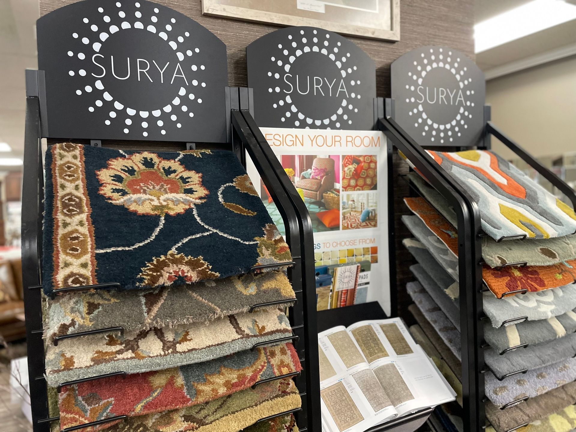 Rug display with stacked patterned carpets and sample boards in a showroom