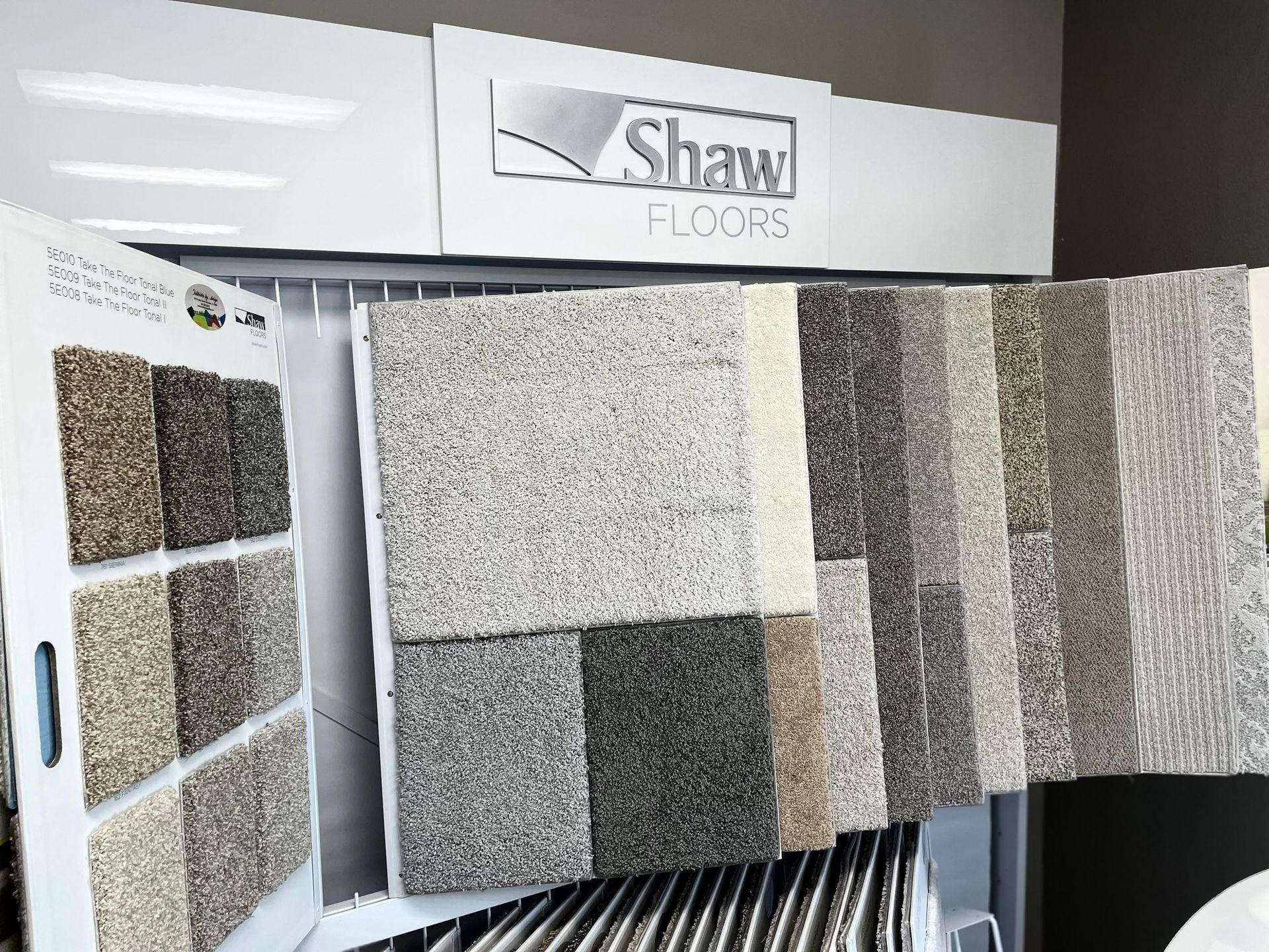 Shaw Floors carpet samples displayed in a showroom on a wall rack