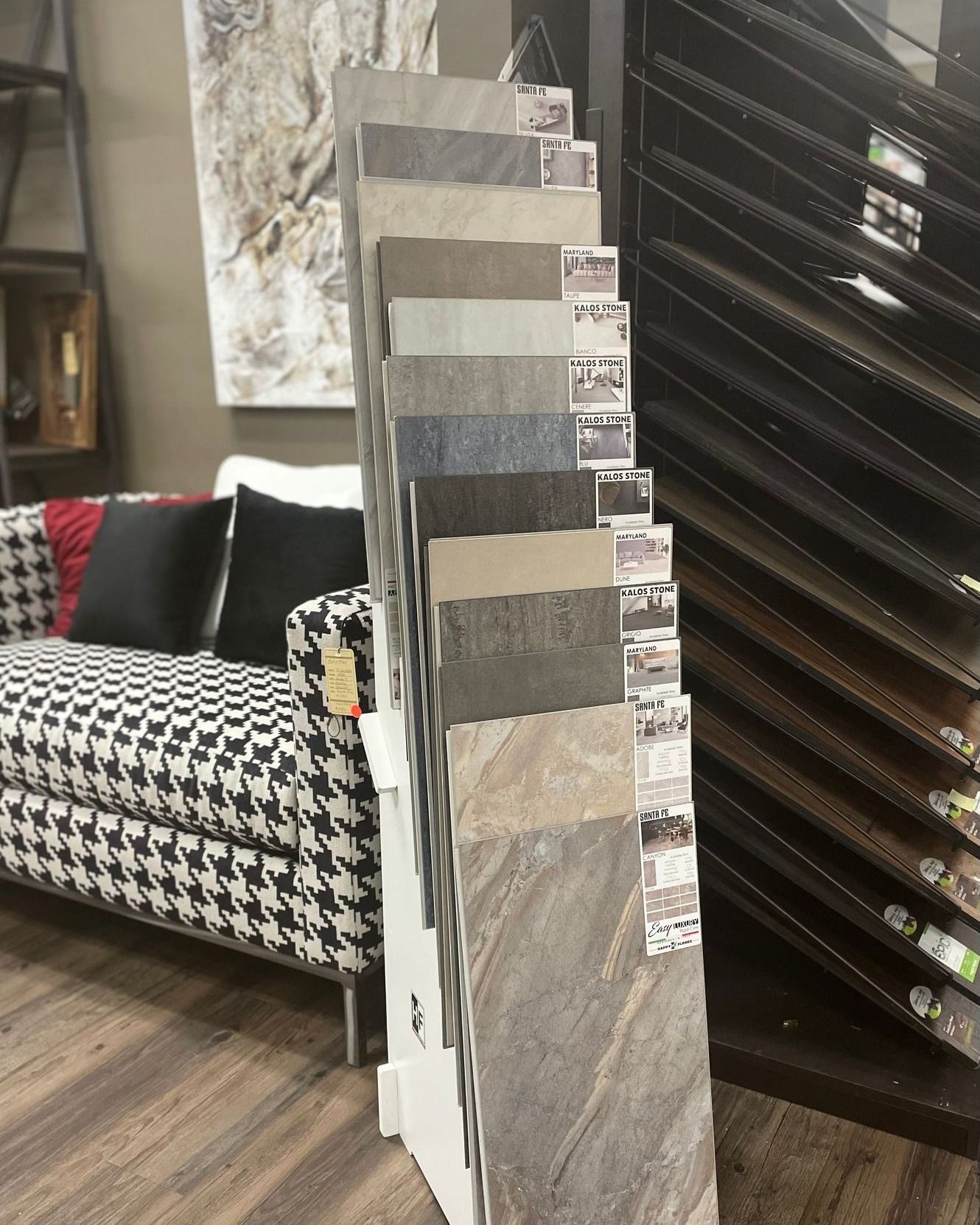 Floor-standing display of marble and tile samples in a showroom, with a patterned chair nearby.