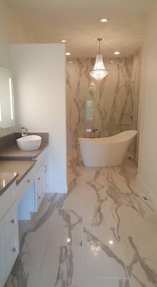 Modern bathroom with marble floors and walls, a freestanding tub, and a double vanity sink.