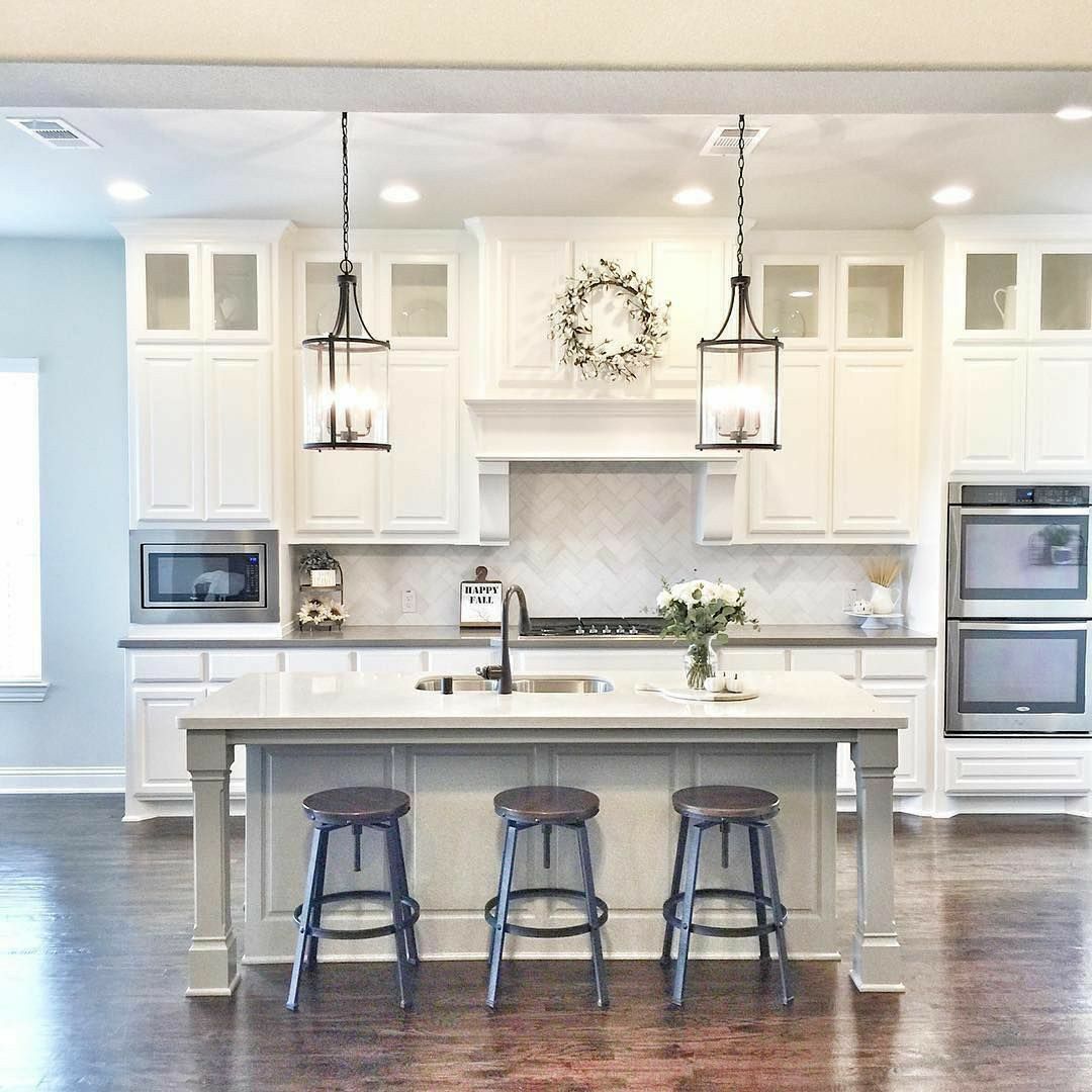 Bright white kitchen with island, three stools, pendant lights, and built-in appliances