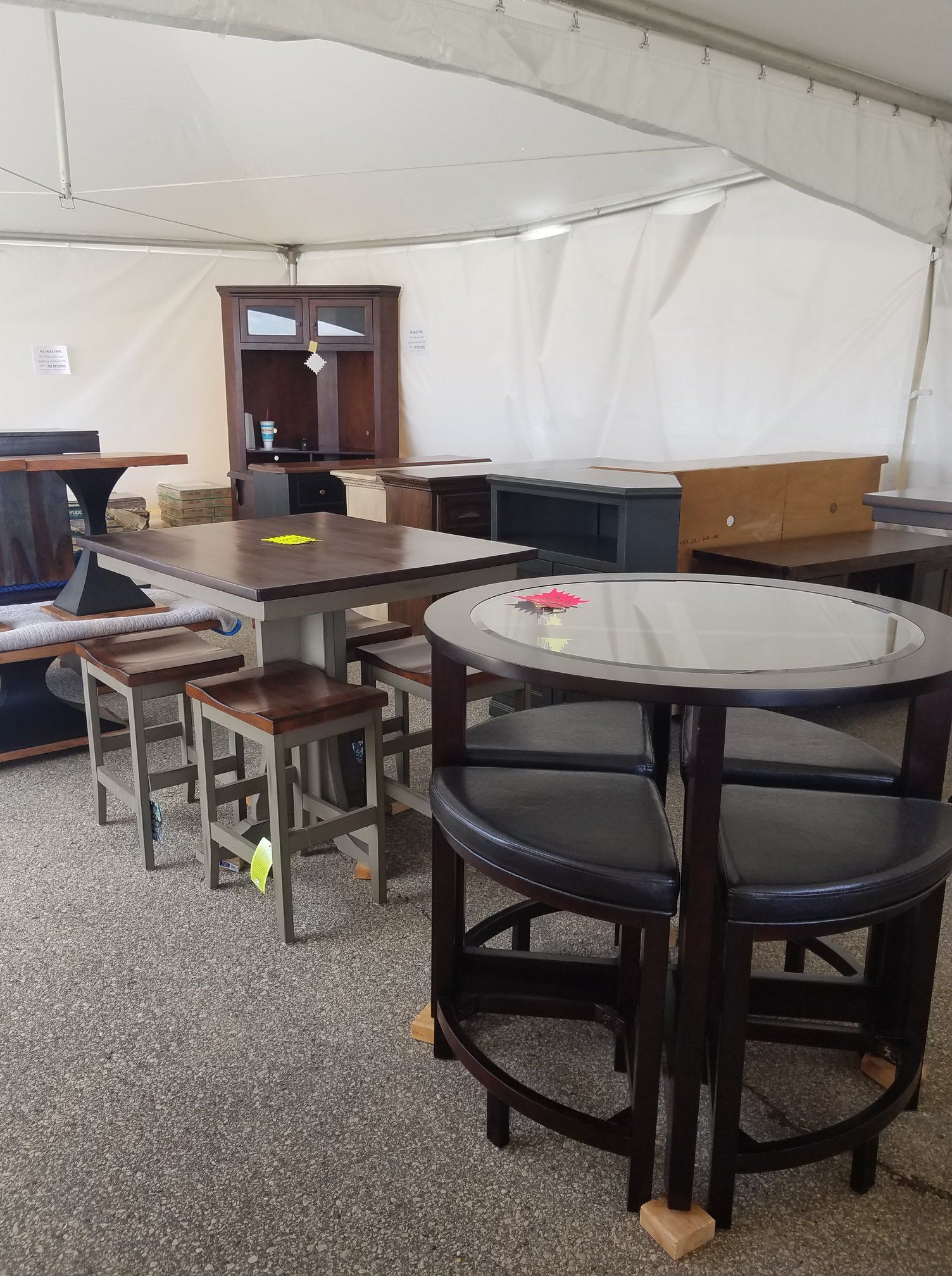 Indoor event tent with round tables and chairs, a cabinet, and table coverings on a carpeted floor.