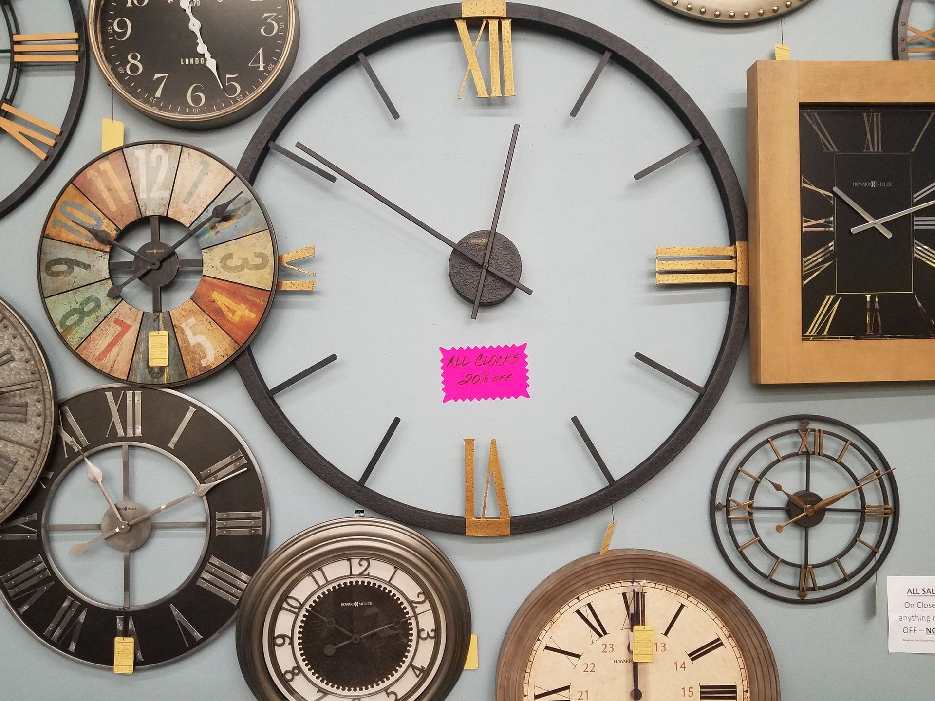 Assorted vintage wall clocks in varied styles and colors, arranged on a display wall