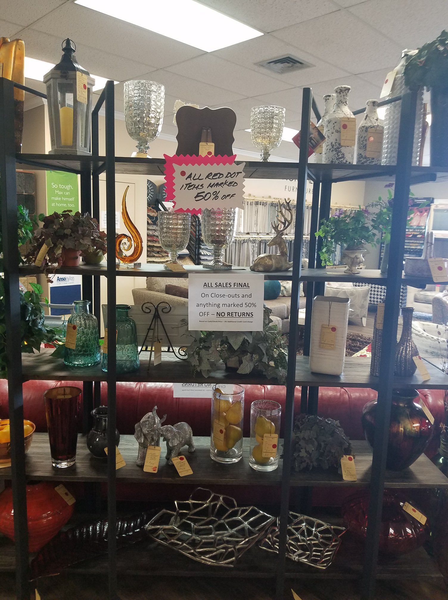 Store display of assorted decorative items and candles on black shelves, with signs in the center.