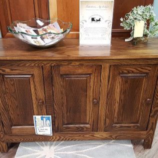 Wooden cabinet with decorative bowl, brochure, and small flower arrangement in a room