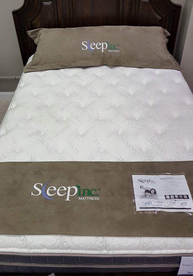 Bed with white quilt and tan Seep mattress topper package on the footboard