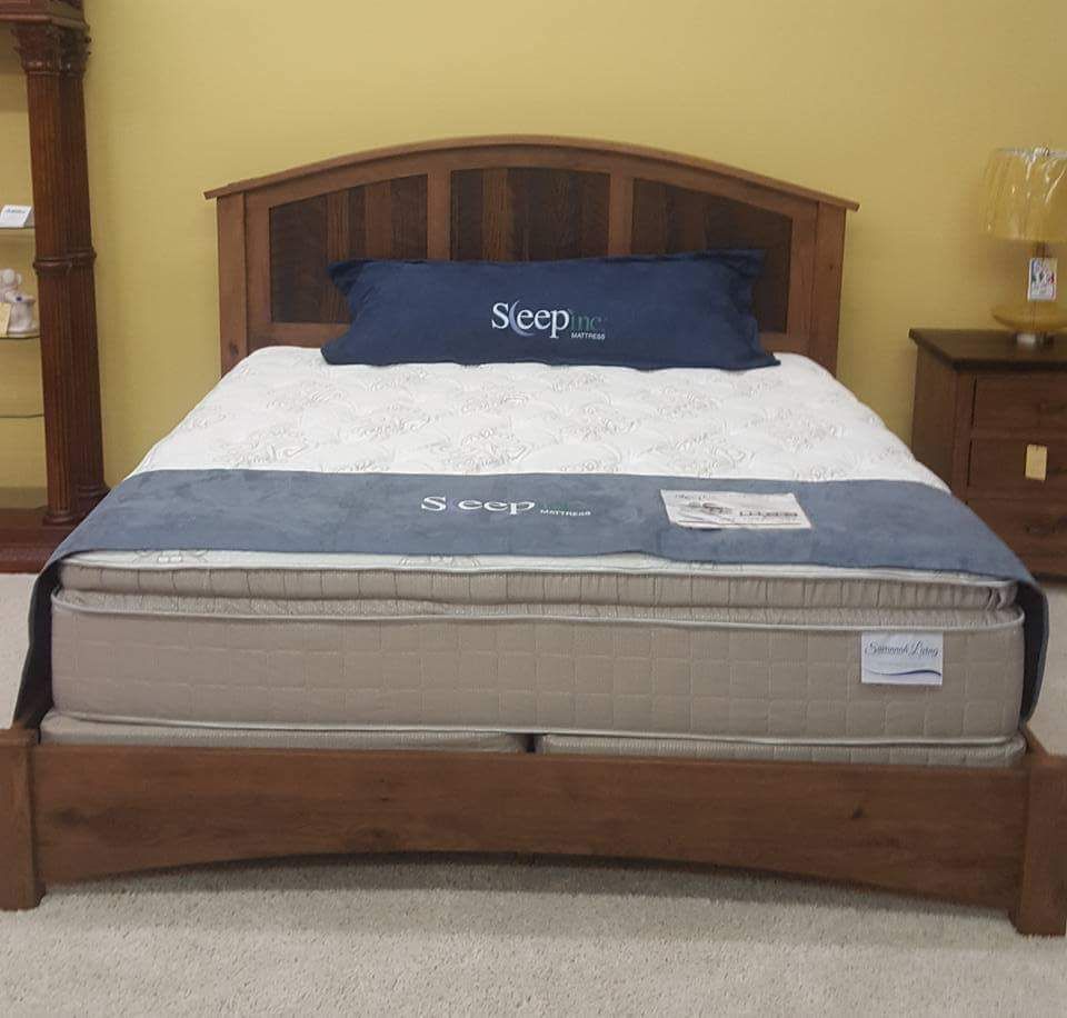 Wooden bed frame with blue bedding and pillows in a furniture showroom