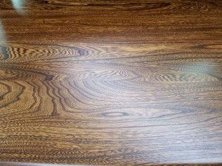 Wooden tabletop with a glossy brown grain pattern and soft light reflection