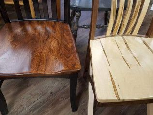Two wooden chairs: one dark polished seat and one light slatted seat on a wood floor.