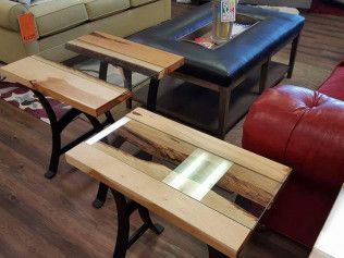 Three small rustic wooden coffee tables with black metal legs in a living room