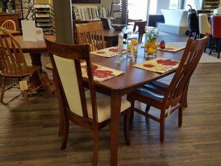 Dining table with chairs in a cozy café, set with condiments and red placemats on a wooden floor.