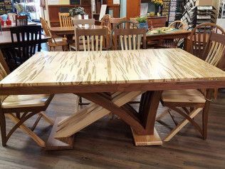 Wooden dining table with a patterned top and geometric base in a furniture showroom