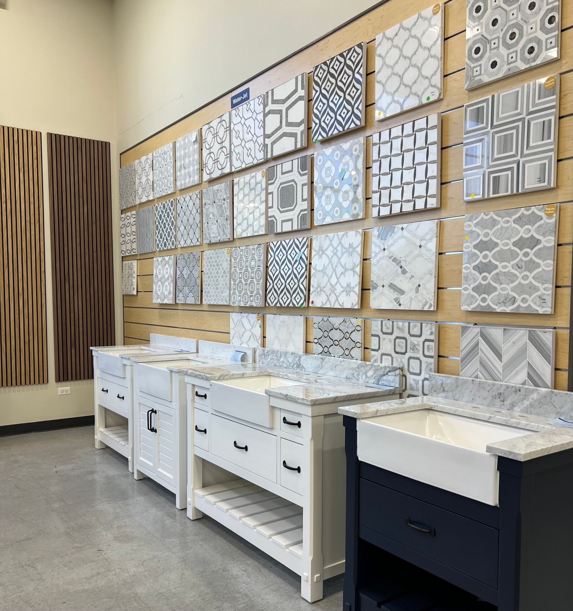 Display of decorative tile samples and white sink vanities in a showroom