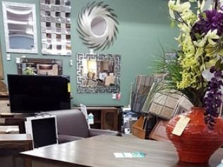 Decorated office or reception area with computer monitors, a desk, wall art, and a large floral arrangement.