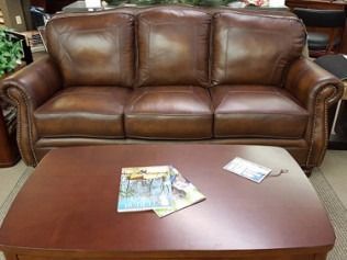 Brown leather sofa behind a wooden coffee table with magazines in a living room