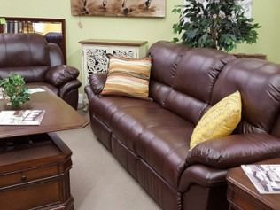 Living room with brown leather sofa, matching armchair, coffee table, and decorative pillows