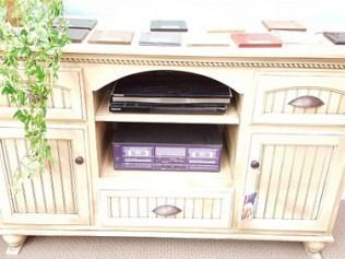 Wooden TV cabinet with a black media player and purple game console in the center shelves