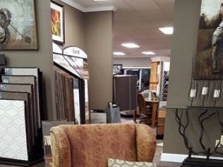 Furniture showroom interior with rugs, wall art, and chairs under bright ceiling lights