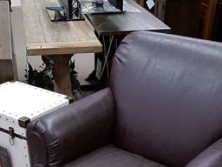 Brown leather armchair beside a white trunk in a small shop or café seating area
