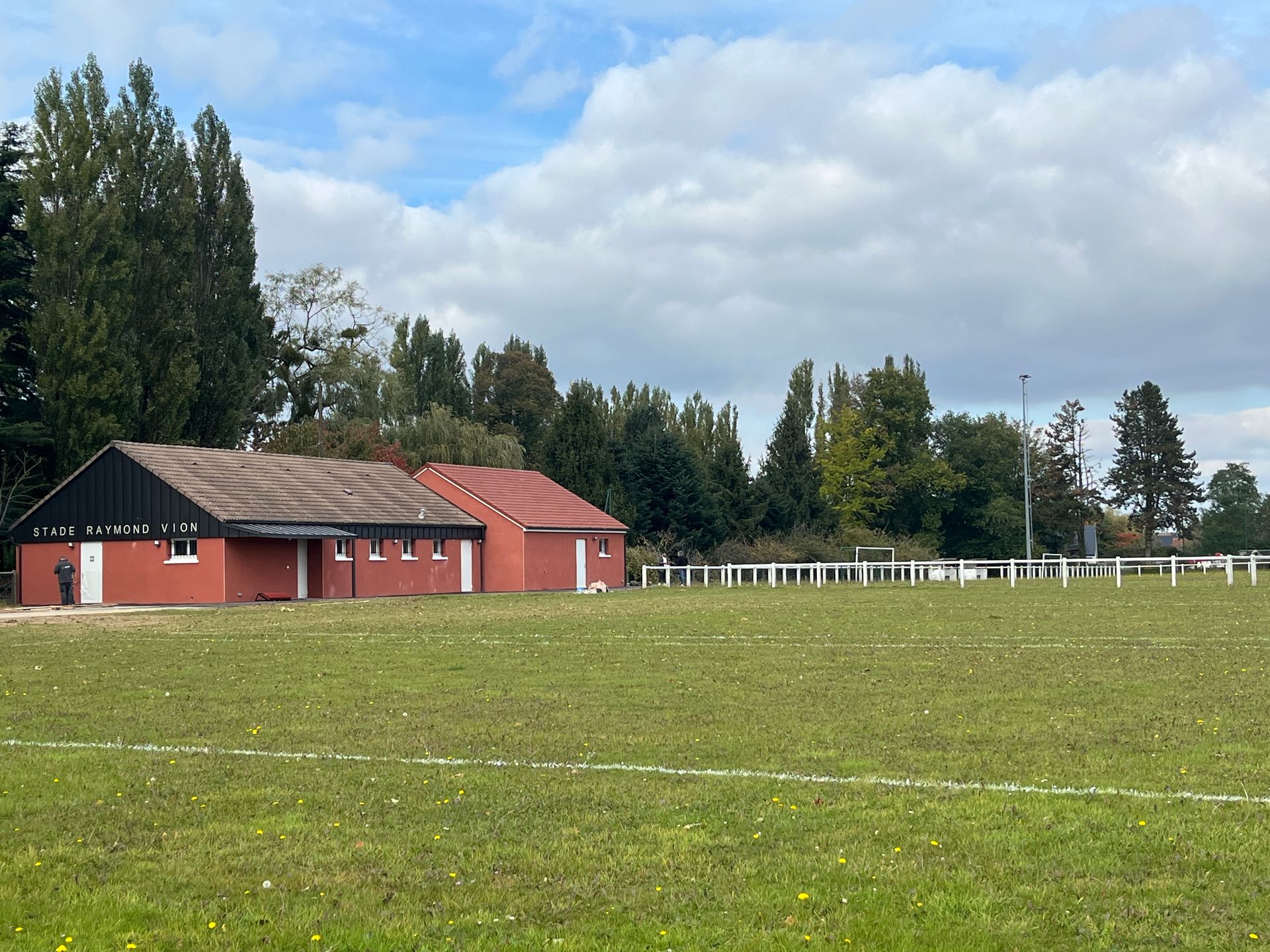 Une salle de classe lumineuse avec plusieurs planches à repasser alignées près de grandes fenêtres et une grande table sur la droite.