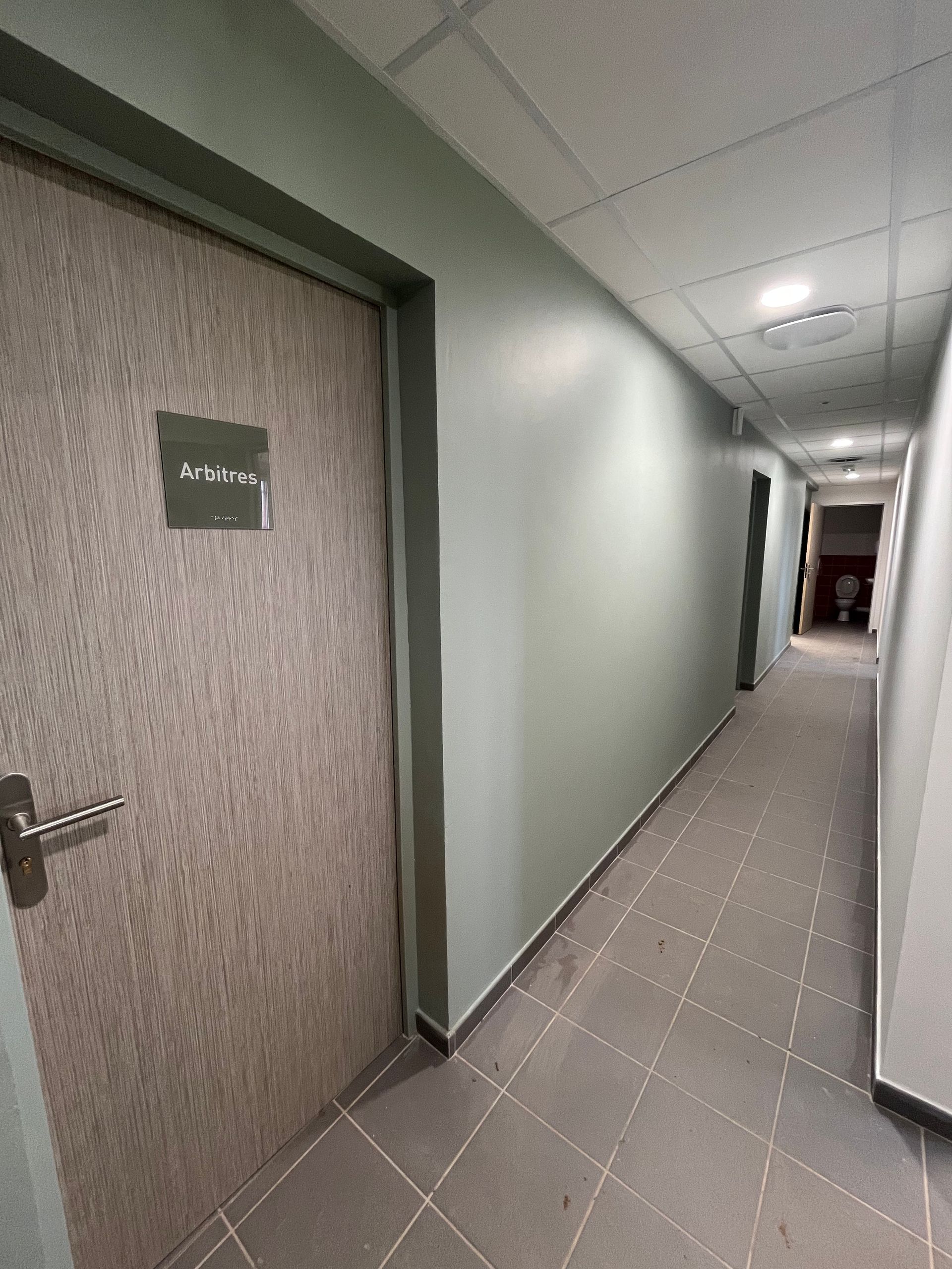 Une buanderie ou une salle de classe textile comprenant plusieurs tables à repasser recouvertes de housses bleues et des rangées de chaises et de tables.