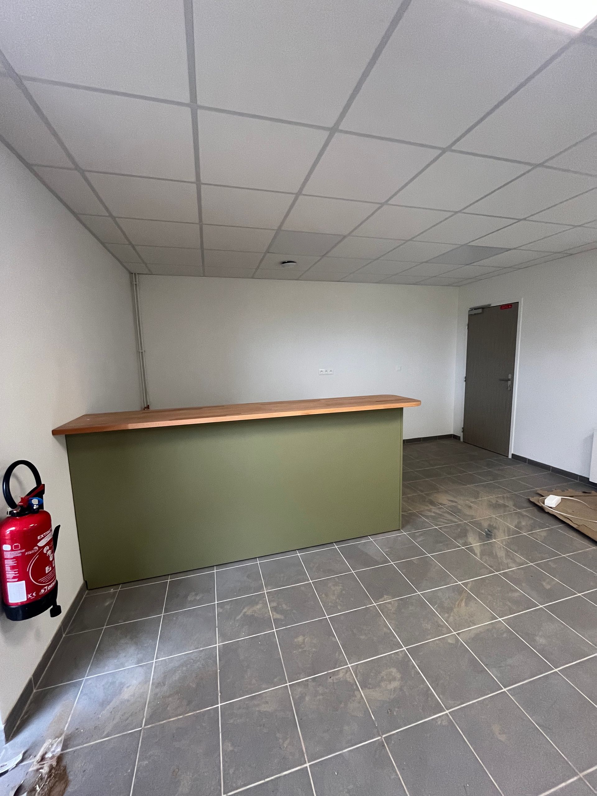 Une salle de classe avec des tables mobiles et des tabourets rouges, un lavabo et un distributeur d'essuie-mains en papier.