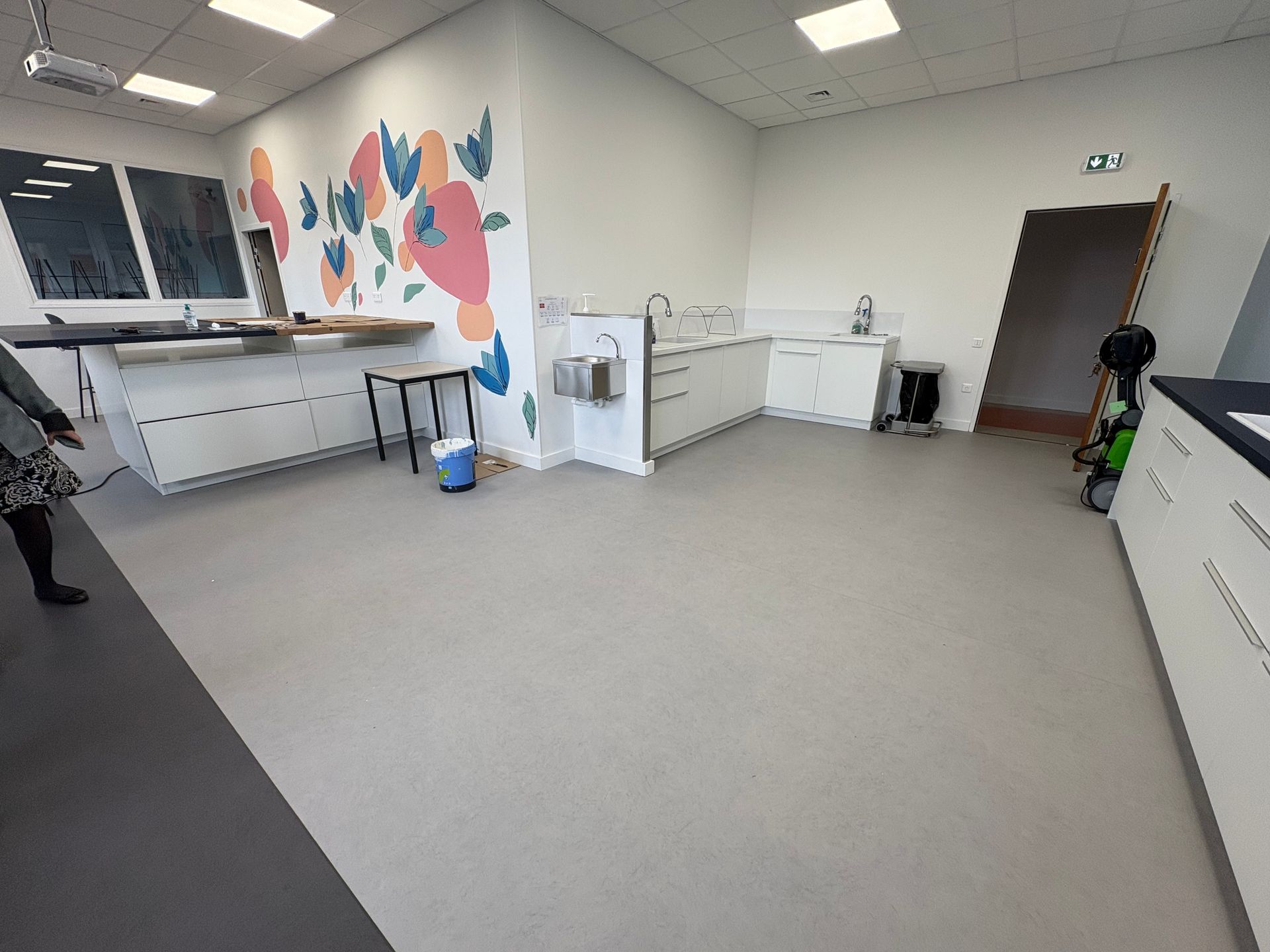 Une salle de classe moderne et lumineuse, avec des paillasses de laboratoire blanches, une fresque colorée au mur et un agencement propre et ouvert.