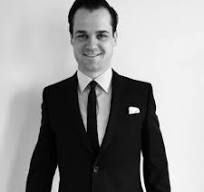 A man in a suit and tie is smiling in a black and white photo.